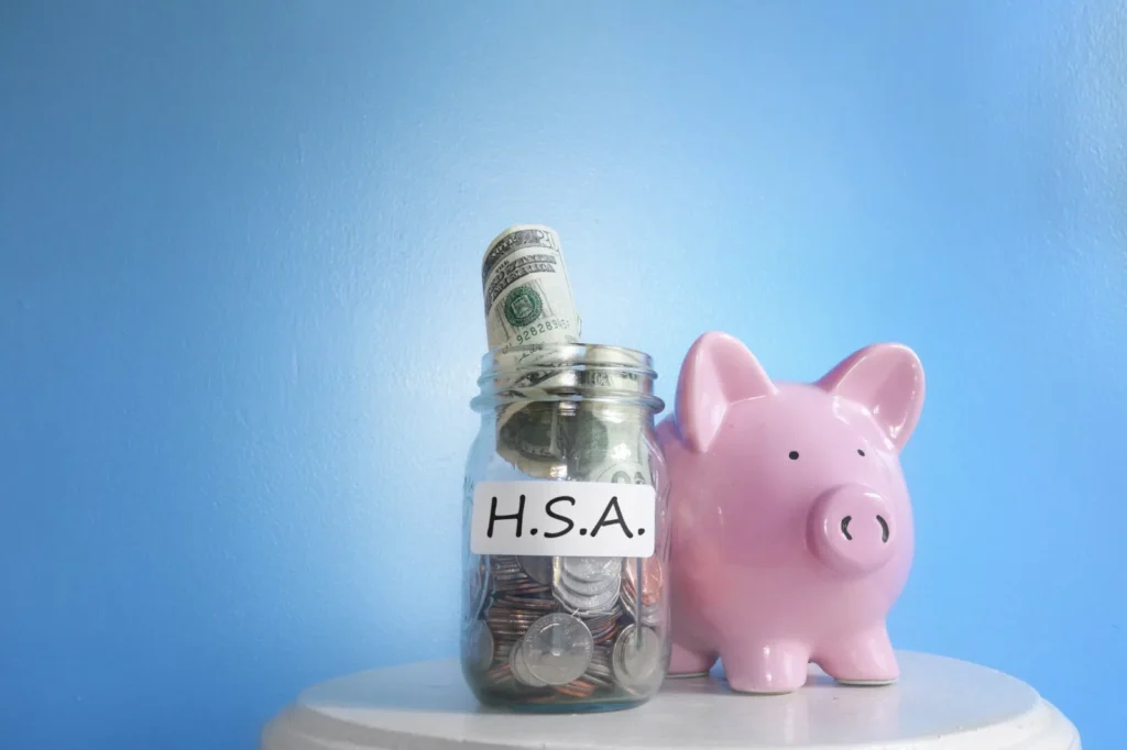 piggy bank next to jar of coins labeled for health savings account for lasik surgery