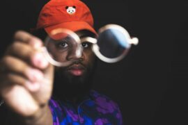 man in read cap and beard holding glasses