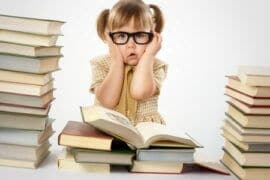 Young girl in glasses between stack of books