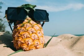 sunglasses on pineapple on beach