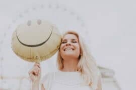 woman holding smiley face balloon