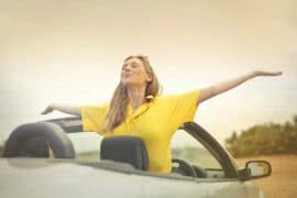 woman standing in parked convertible