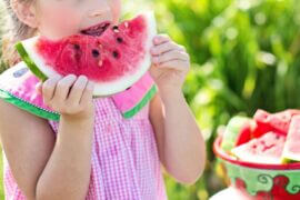 young girl eating watermelon outdoors on summer day